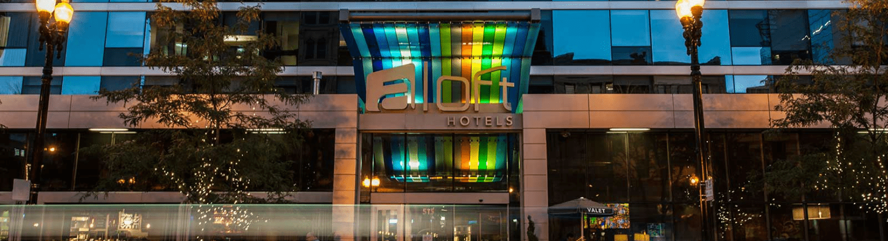 The front entrance of Aloft hotel, with a rainbow awning