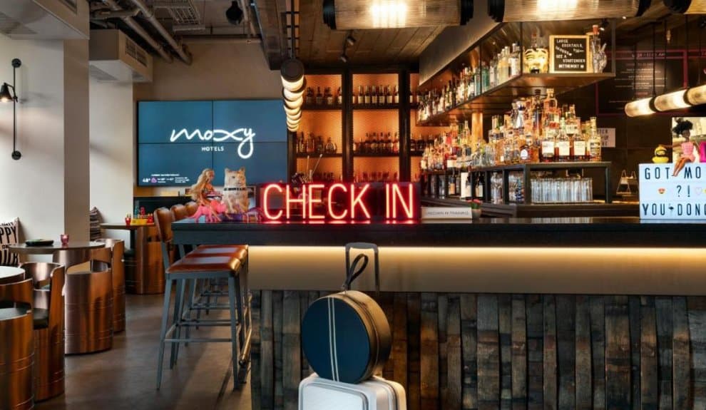 A hotel bar area with a glowing 'check-in' sign