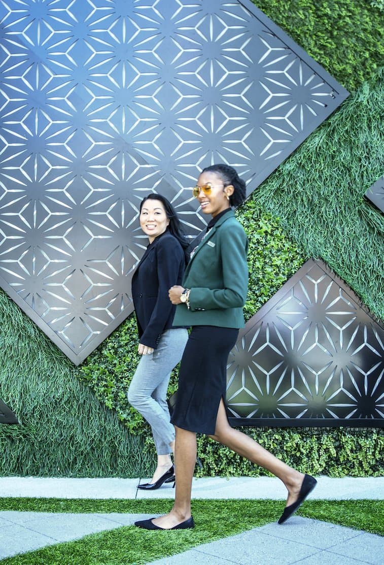 Two hotel associates walking in front of a green wall