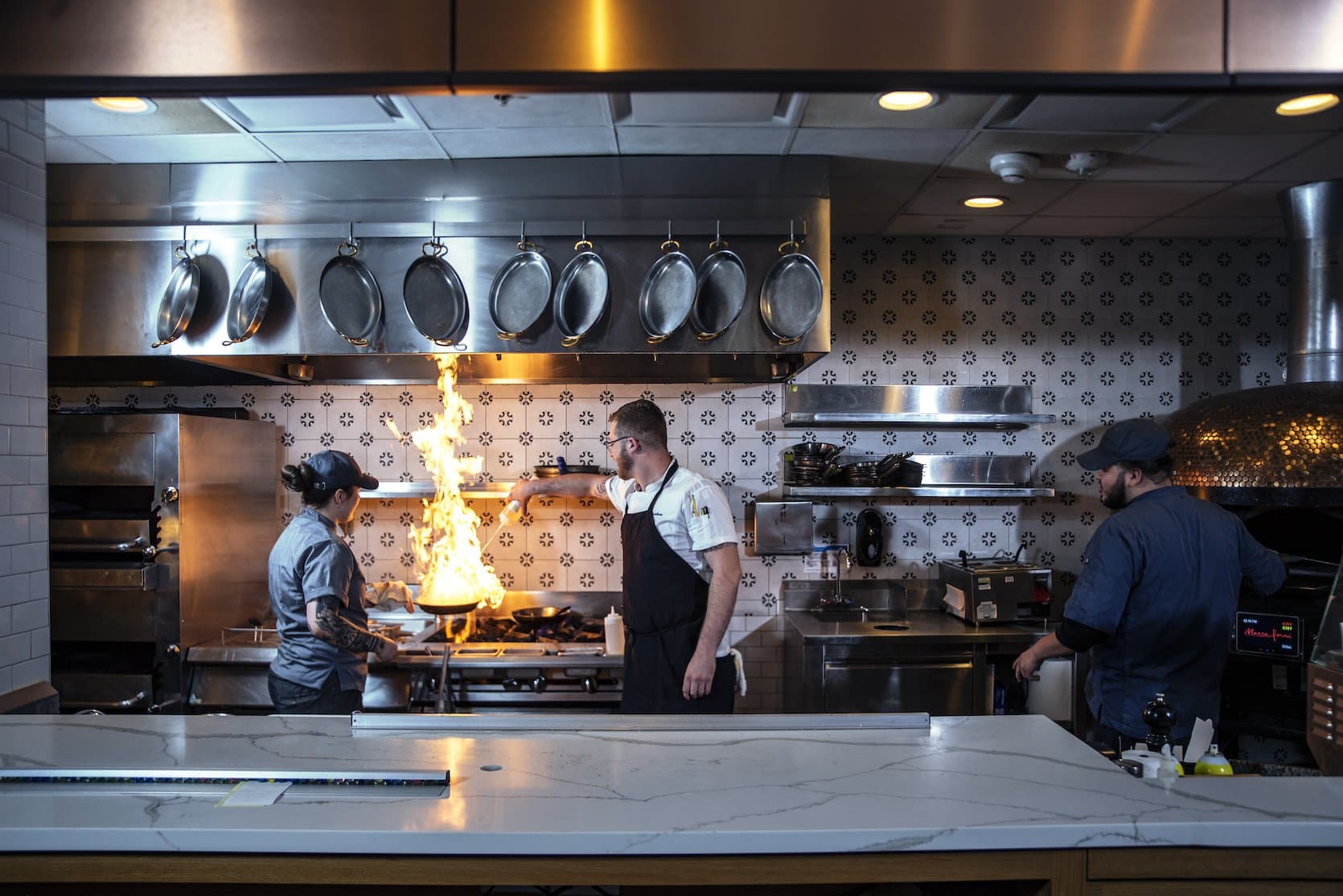 Chefs working in a kitchen over a flaming pan